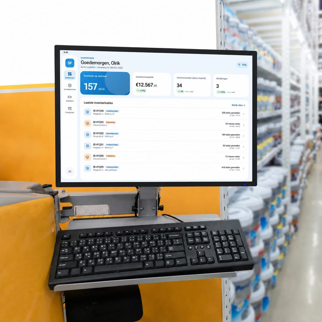 Een monitor op een werkstation in een magazijngang toont het STOCKflow-dashboard met voorraadaantallen.