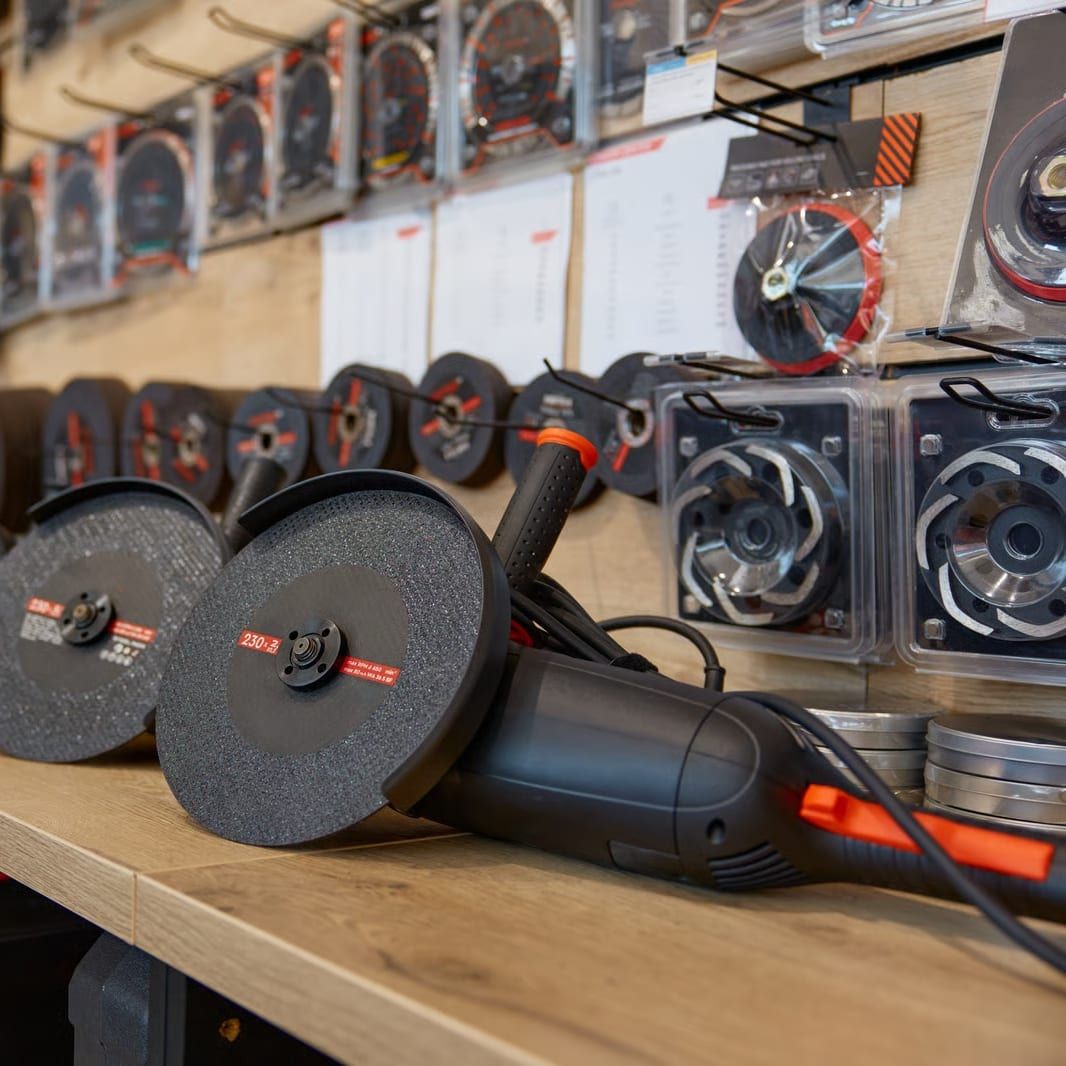 Een schap met slijpschijven en een haakse slijper, met gereedschap aan de wand erachter.