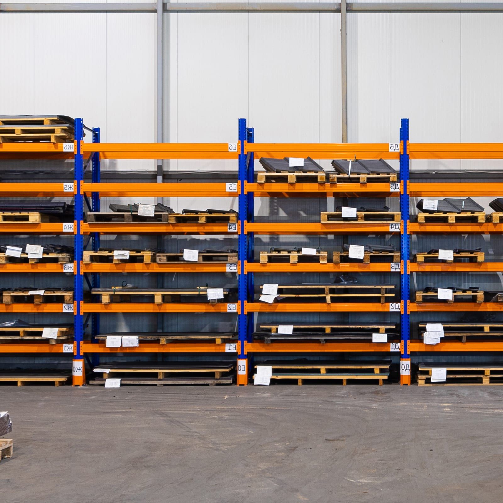 Stellingen met plaatmateriaal en pallets in een bedrijfshal.