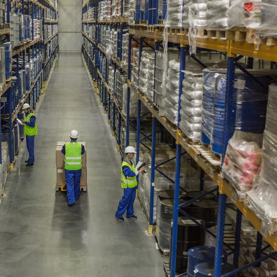 Een medewerker inventariseert voorraad met een RFID-reader in een gang met hoge magazijnstellingen.