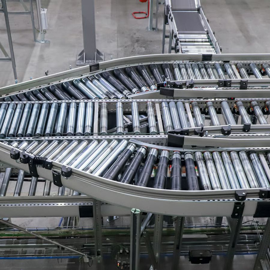 Rollenbanen die elkaar kruisen in een distributiecentrum, met dozen onderweg naar de volgende afdeling.