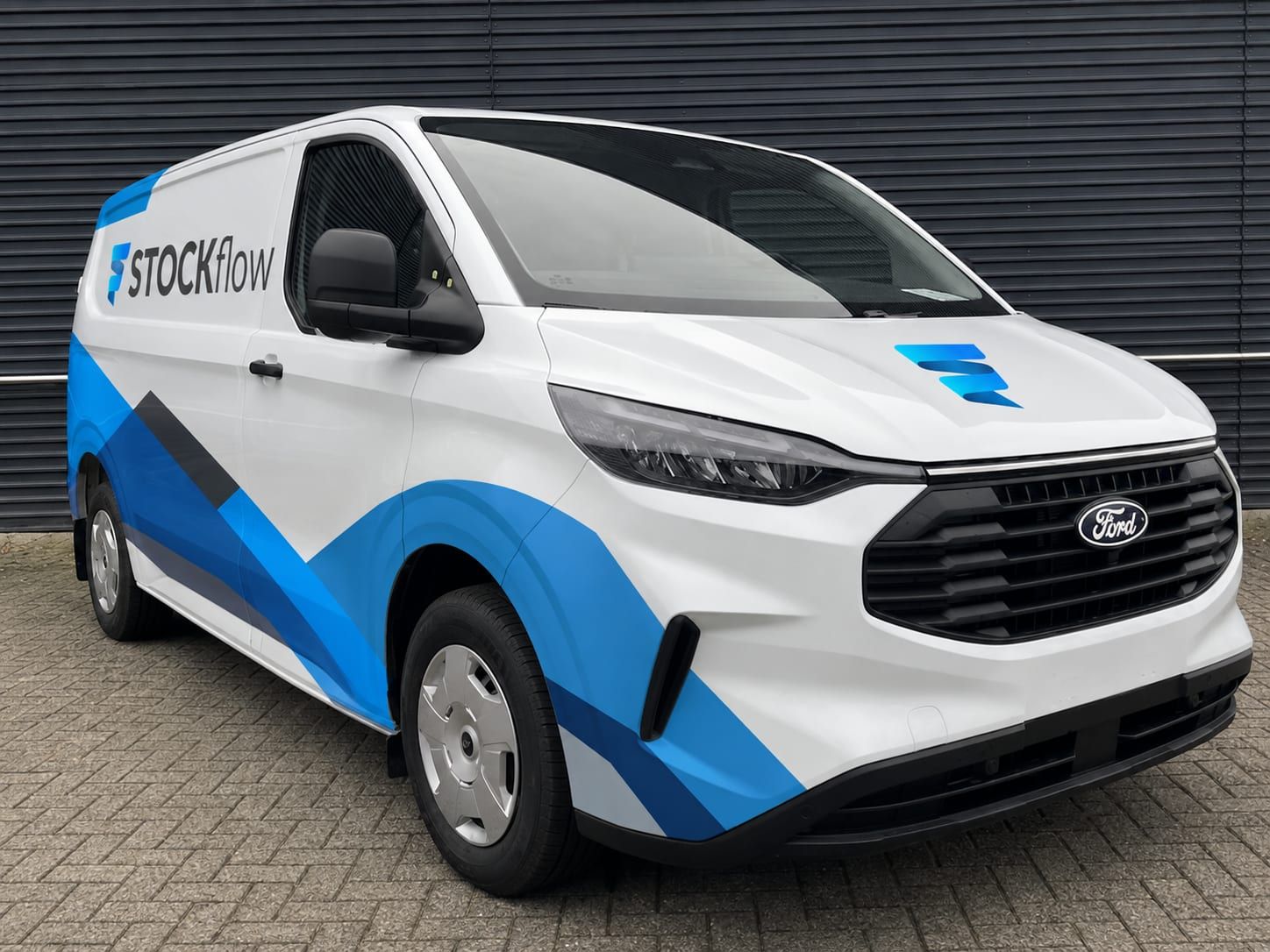 De bestelbus van STOCKflow, wit met blauwe belettering en het STOCKflow-logo op de zijkant.